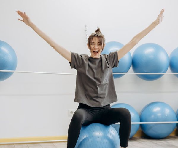 Smiling woman stretching in a bright room with coral light.